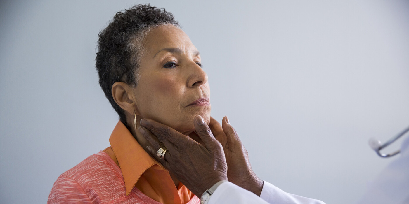 A doctor feels the neck of a female patient
