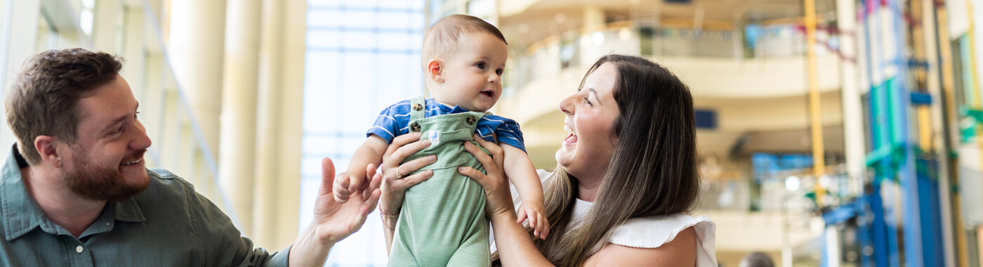 Una madre y un padre juegan con su bebé en el vestíbulo de Duke Children's.