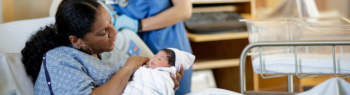 A mom holds her newborn baby in a hospital bed