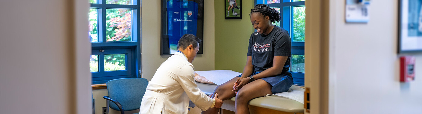 Un médico examina la rodilla de una paciente.