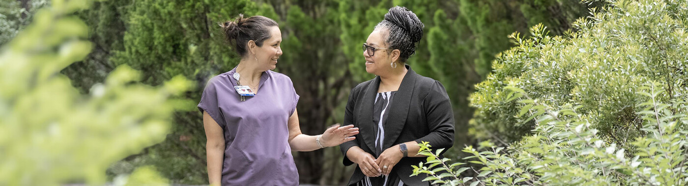 Un proveedor y un paciente caminan por un jardín