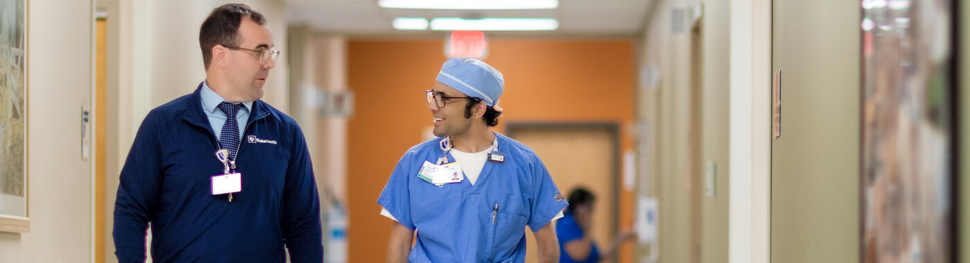 Two doctors chat as they walk down a hallway