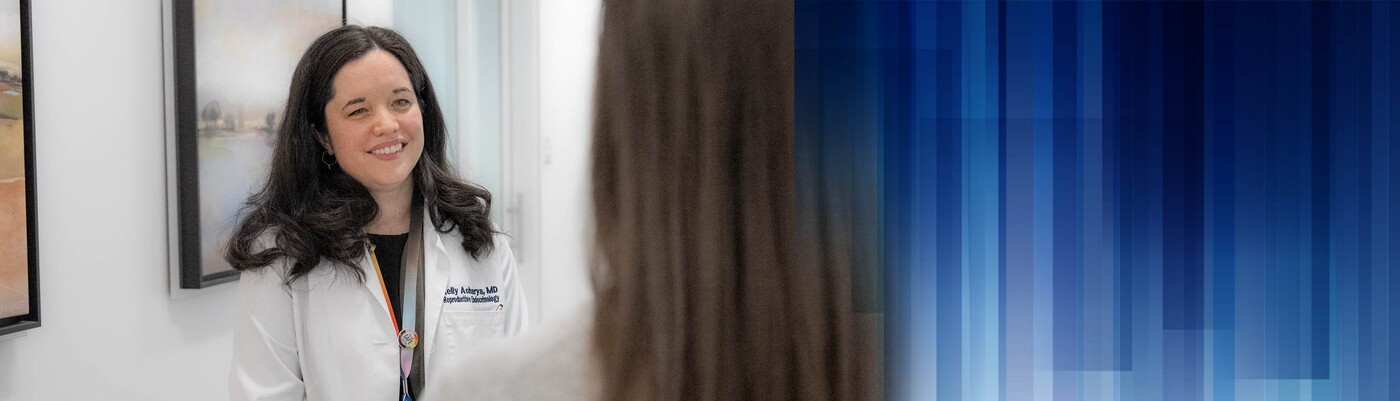 A provider smiles as she talks with a patient in a hallway