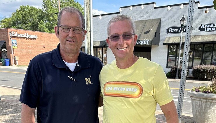 Anthony stands next to David and smiles