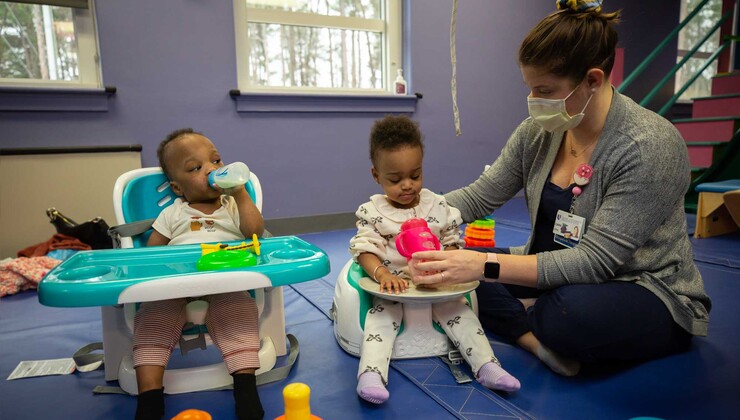 Una terapeuta ocupacional trabaja con la sujeción del biberón con un par de gemelos