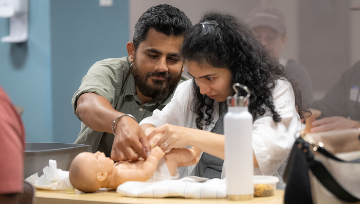 Una pareja practica con un muñeco cómo cambiar un pañal