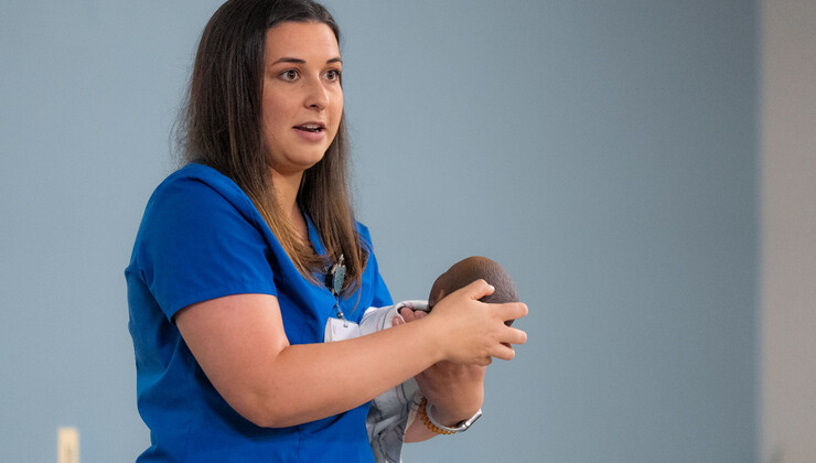 Una enfermera usa un muñeco para enseñar los cuidados del recién nacido y habilidades de seguridad durante una clase de preparación para la llegada del bebé.