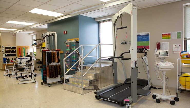 El gimnasio de última generación del Duke Rehabilitation Institute ofrece a los pacientes una amplia variedad de equipos de gimnasia e incluye un dispositivo de asistencia para caminar que ayuda a los pacientes a moverse por el área del gimnasio.