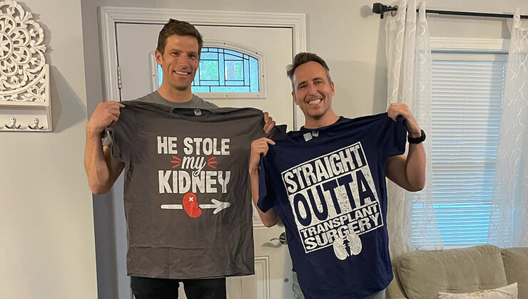 Zach Stroud and Josh Jones stand holding t-shirts