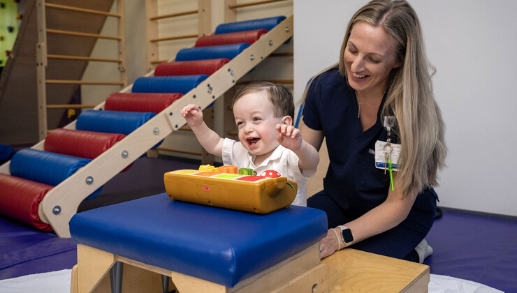 A therapist helps a patient sit while he plays with a toy