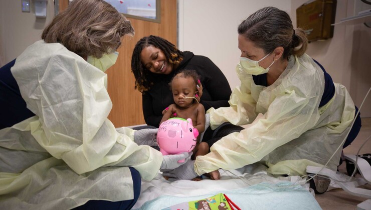 Dos terapeutas juegan con un paciente pequeño y su madre durante una sesión de terapia ocupacional en el hospital