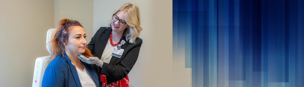 A provider feels a patient's neck in a clinic room