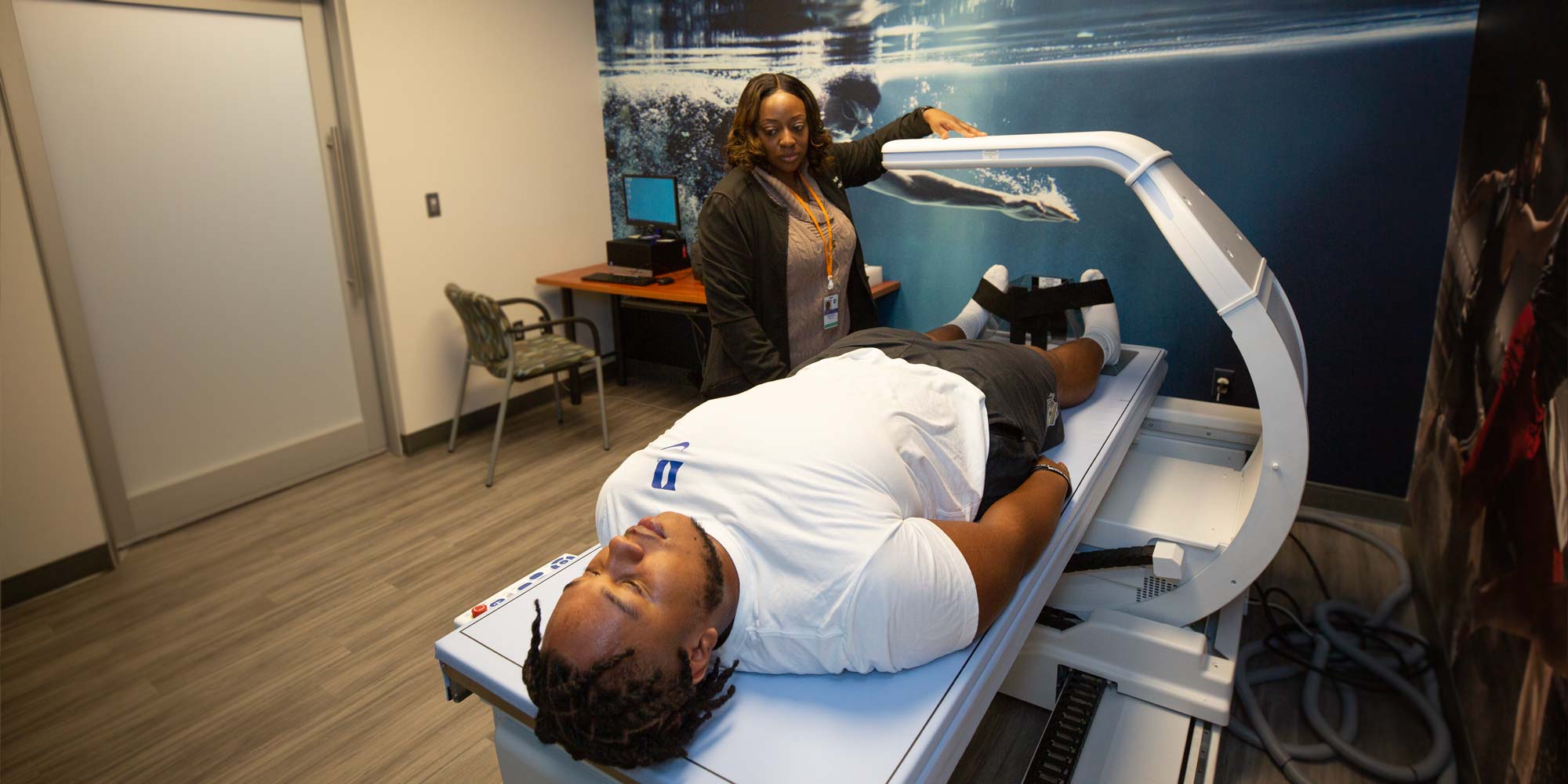 A provider sets up a scan while an athlete lies on a table for the scan