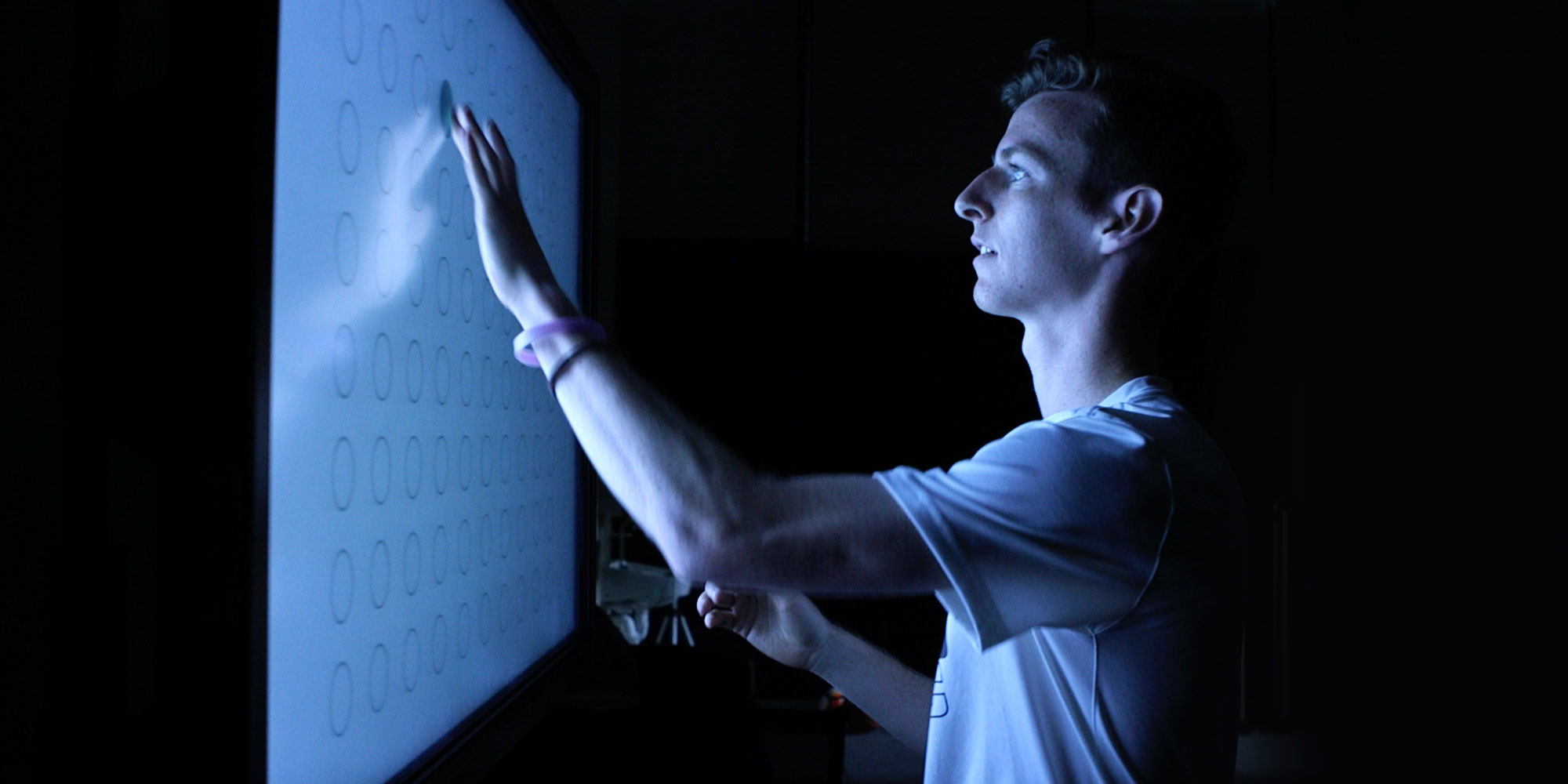 A man taps circles as the light up during a sports vision test
